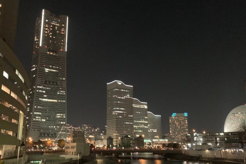 A city skyline at night with illuminated buildings and a river in the foreground. 3