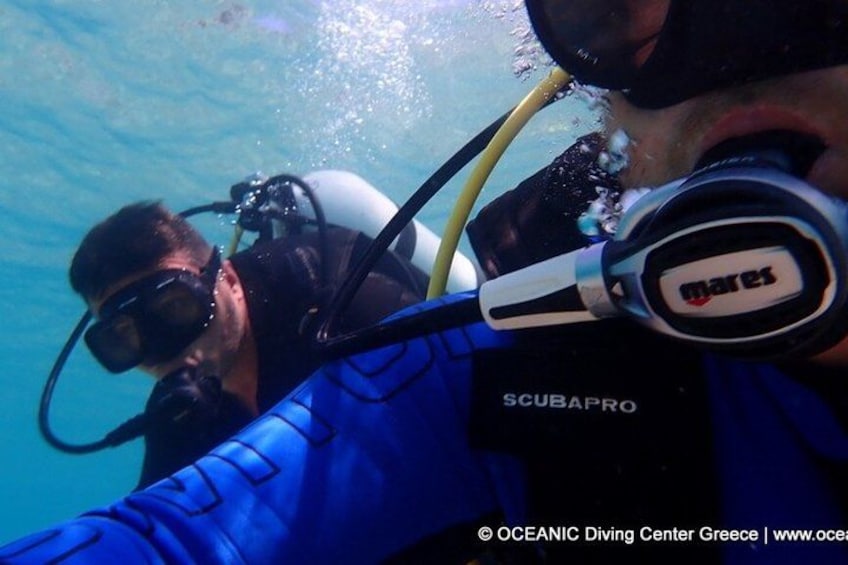 Two scuba divers underwater with SCUBAPRO gear and a brand name 'mares' on the regulator. 3