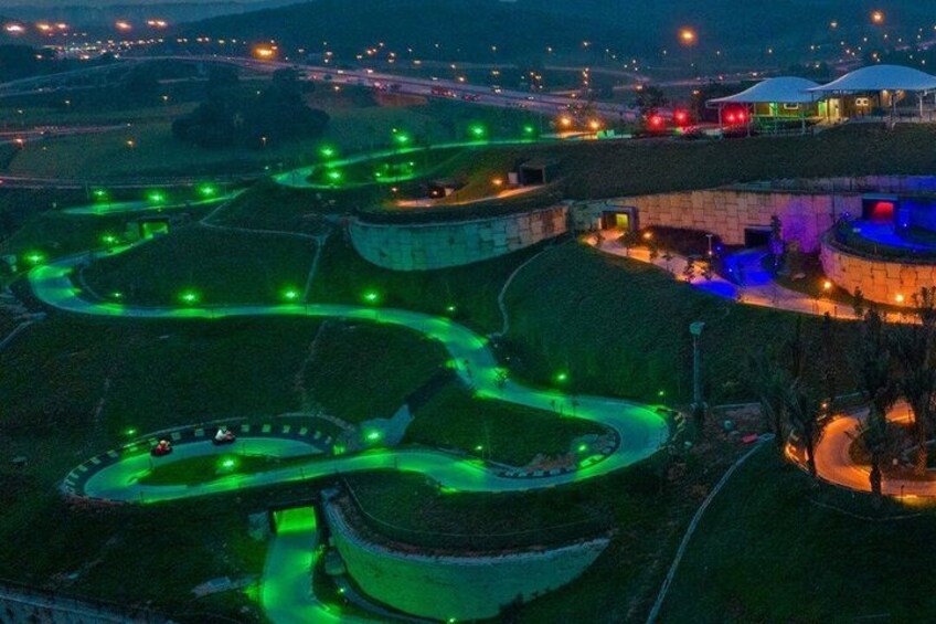A nighttime view of a large, illuminated complex with winding roads and circular structures. 3