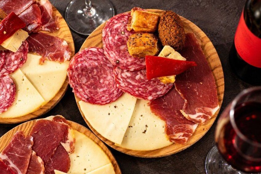 A variety of cured meats and cheeses on wooden boards. 2