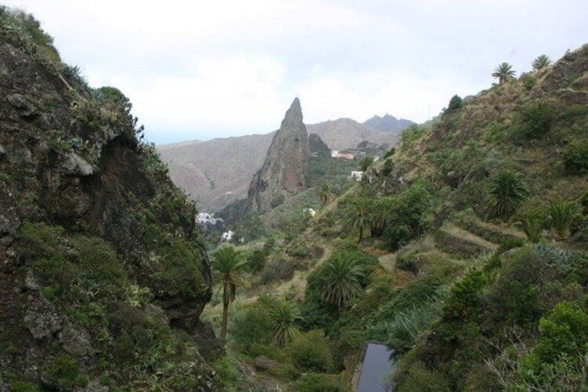 A mountainous landscape with a prominent rock formation, lush greenery, and terraced fields. 1