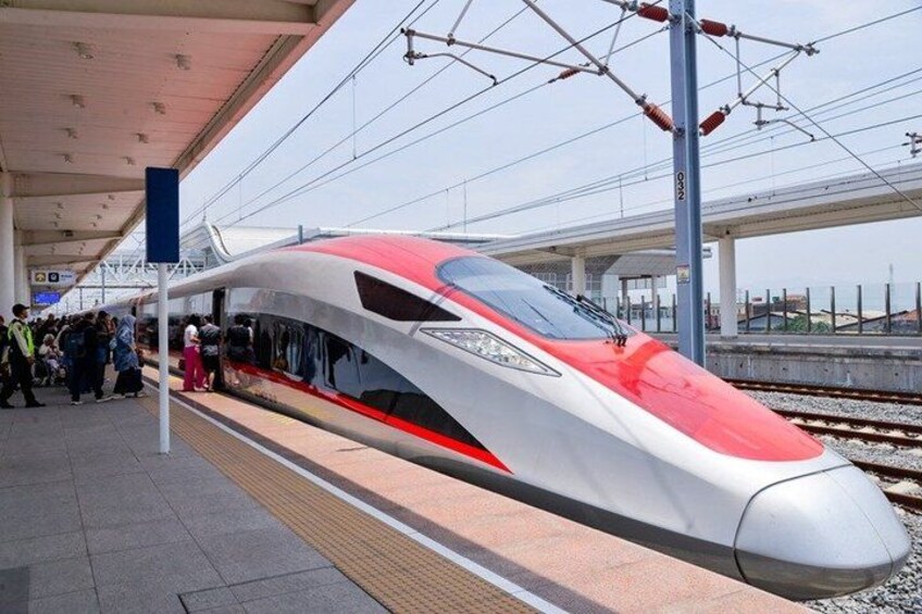 A high-speed train at a station platform with passengers waiting. 1