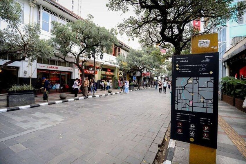 A city street with shops, trees, and a map sign. 5