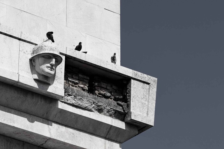 A stone monument with a carved face and birds perched on it. 3