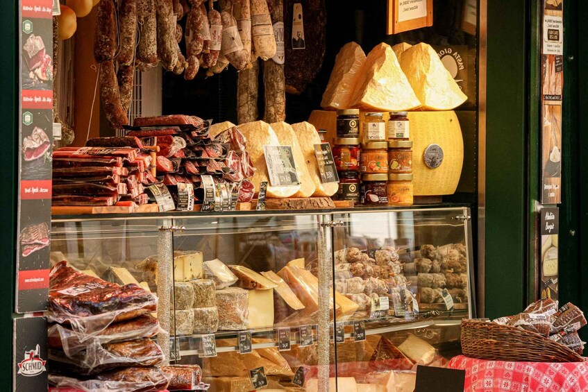 A variety of cheeses and cured meats displayed in a shop window. 2