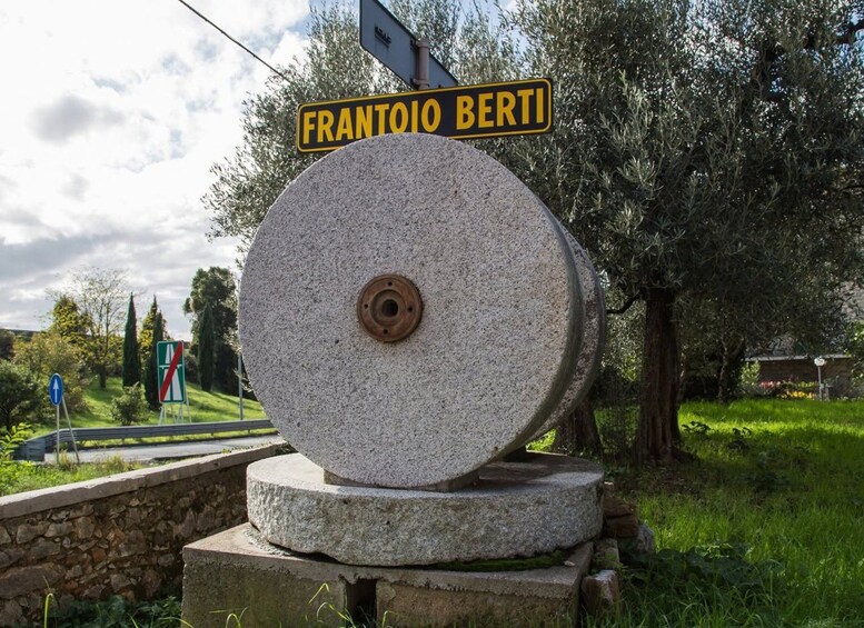 A large stone millstone with a sign above it reading 'FRANTOIO BERTI'. 5