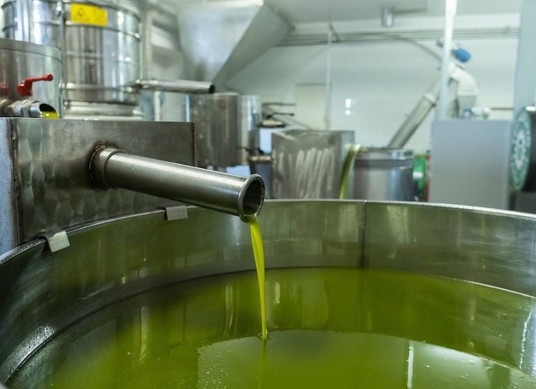 A stainless steel tank with a yellowish liquid being poured out. 5