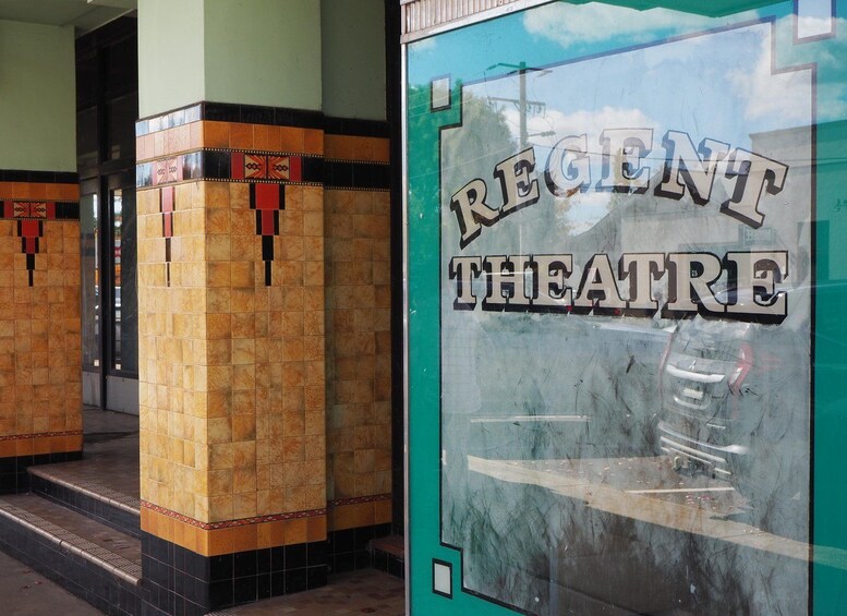 Een bord van het Regency Theatre, met een reflectie van een auto en een gebouw op de achtergrond. 3