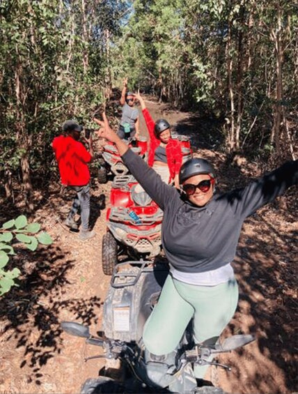 Une personne conduit un quad dans une zone boisée, parmi les arbres, sur un chemin de terre. 1