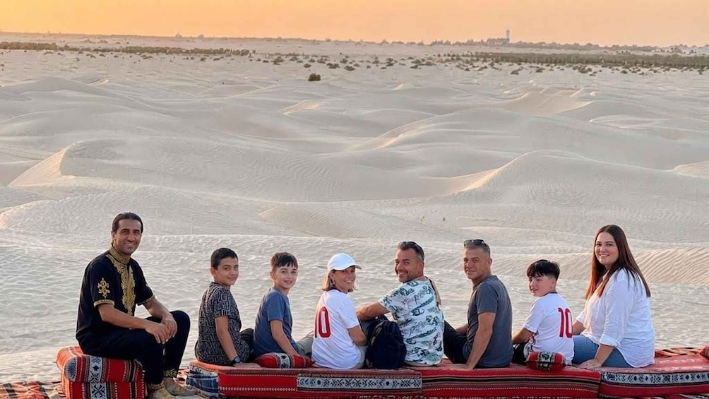 Un groupe de personnes est assis sur un bateau dans un désert, avec des dunes de sable en arrière-plan. 1