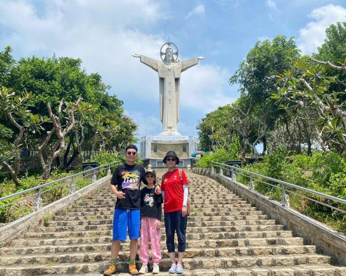 Una familia parada sobre escalones de piedra con una estatua al fondo. 4