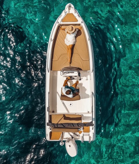 Un petit bateau avec deux personnes à bord, dont l’une porte un chapeau, flotte sur une eau turquoise et limpide. 4