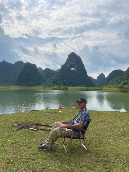 Une personne assise sur une chaise, près d’un lac, avec des montagnes en arrière-plan. 4