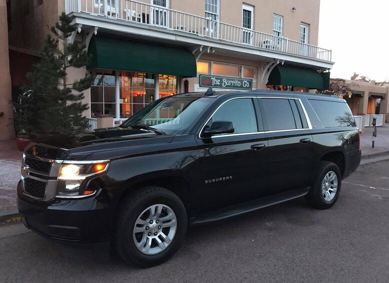 Un SUV negro estacionado frente a un edificio con un toldo verde y un letrero que dice 'The Burrito Co.' 2