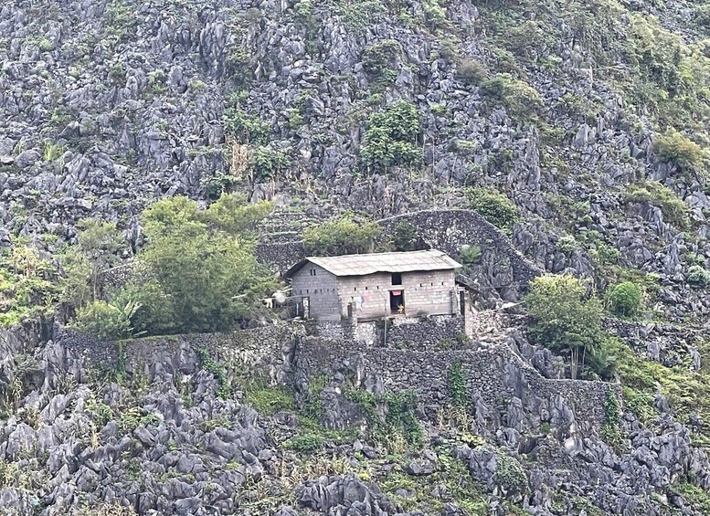 A small stone house surrounded by rocky terrain and sparse vegetation. 2