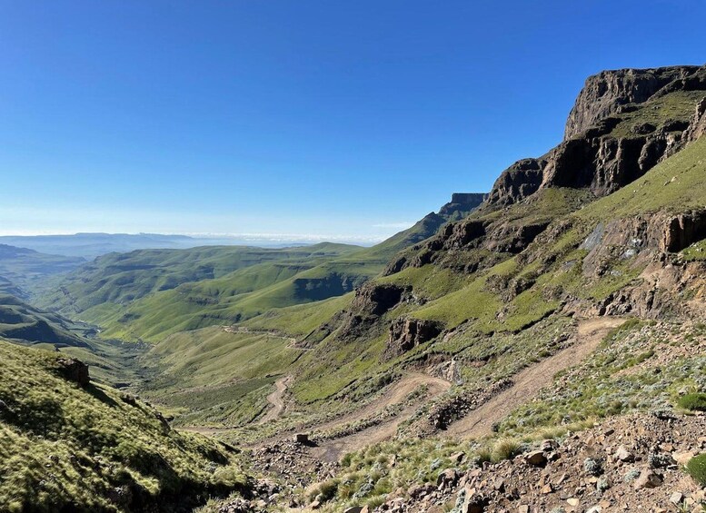A mountainous landscape with a clear sky, a winding path, and distant valleys. 4