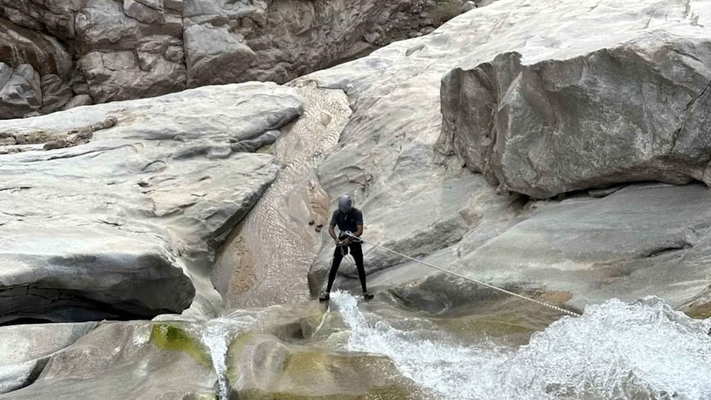 A person rappelling down a rocky cliff. 1