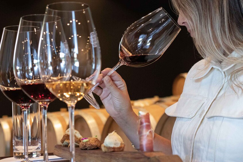 Une personne tenant un verre à vin, entourée de plusieurs autres verres à vin placés sur une table. 4