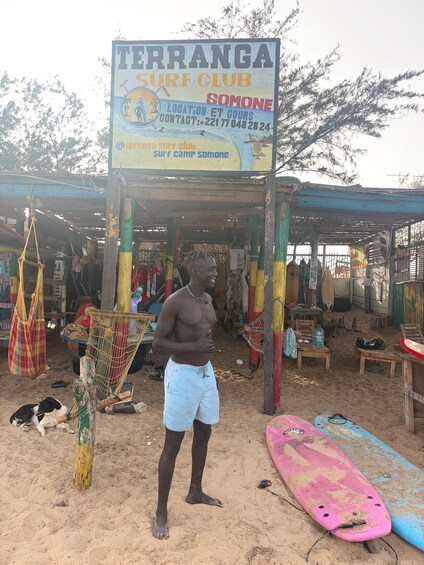 A beach with a sign for the Terranga Surf Club, a dog, and surfboards. 2