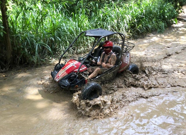 A person in a red and black vehicle navigating through a muddy water crossing. 3