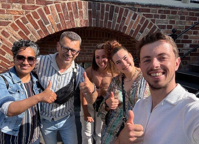 A group of people taking a selfie in front of a brick oven. 1