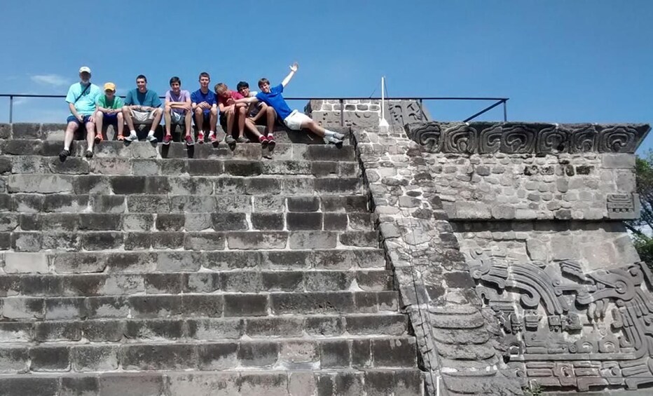 A group of people sitting on stone steps with ancient carvings. 5