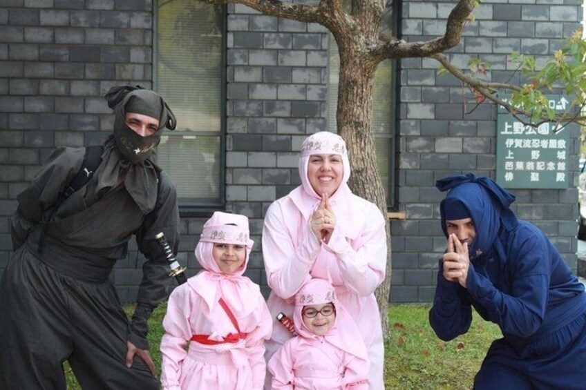 A group of people in costumes, a tree, and a brick building with a sign. 1