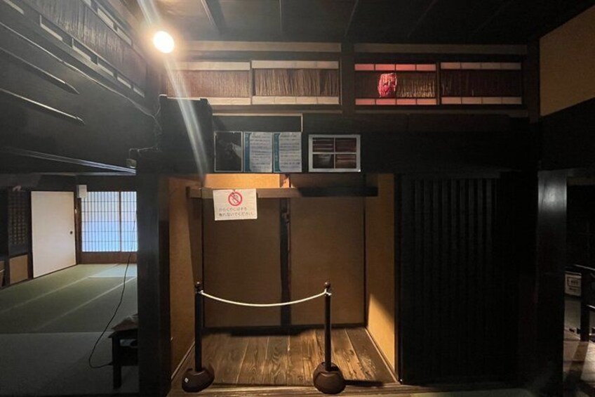 A room with a wooden floor, a white rope barrier, and a sign with a red circle and diagonal line. 5