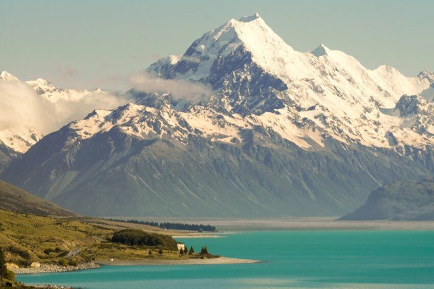 A mountain range with snow-capped peaks, a turquoise lake, and a small settlement on the shore. 4