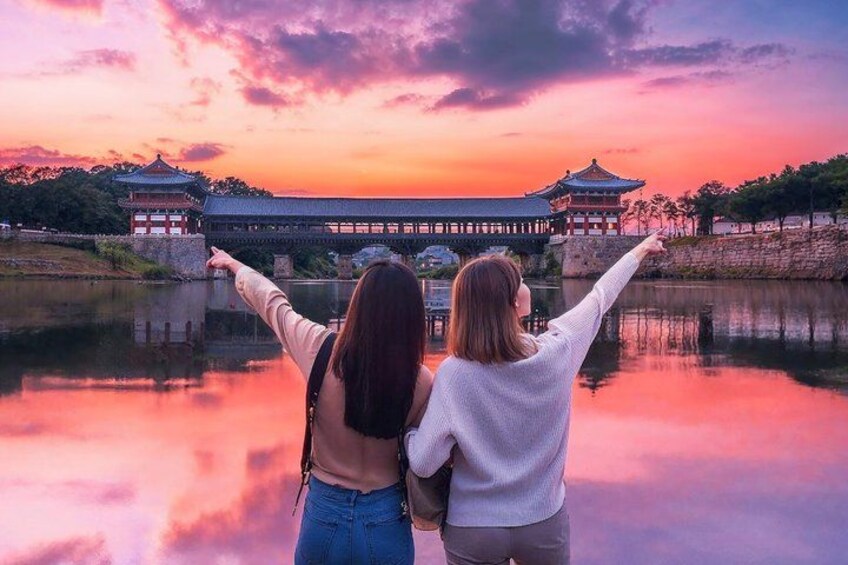 Two people pointing at a traditional building by a calm body of water during sunset. 5