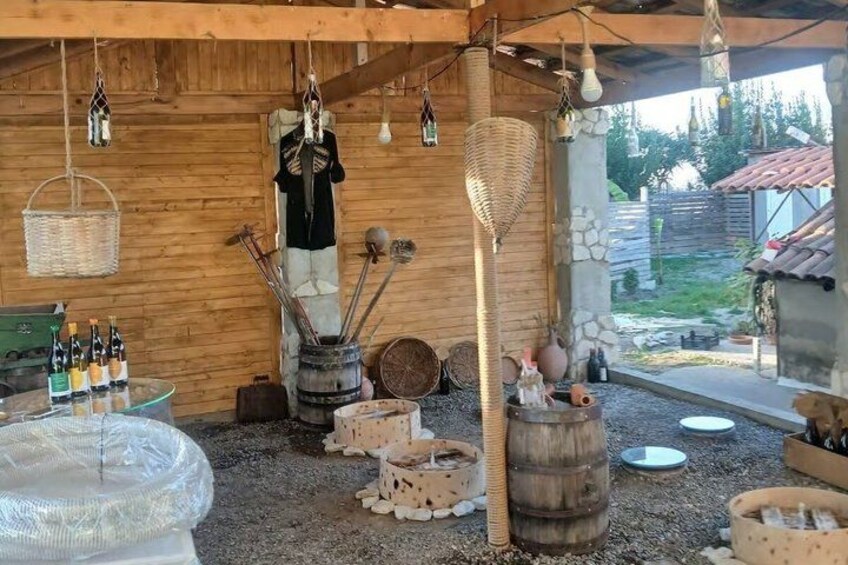 A rustic outdoor setting with wooden structures, a stone wall, and various cooking utensils. 1