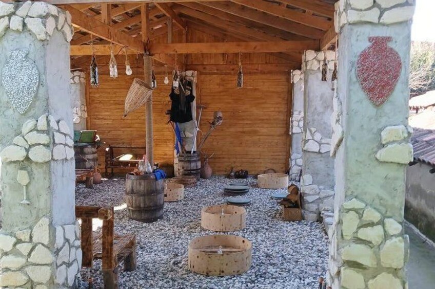 A rustic interior with stone walls, wooden beams, and various tools and containers. 3