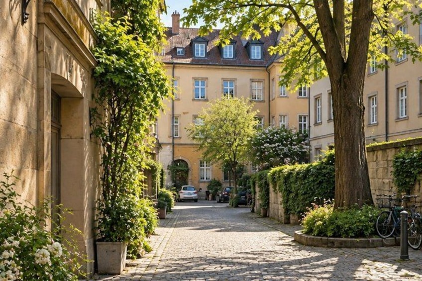A cobblestone street lined with buildings, a tree, and a bicycle. 5