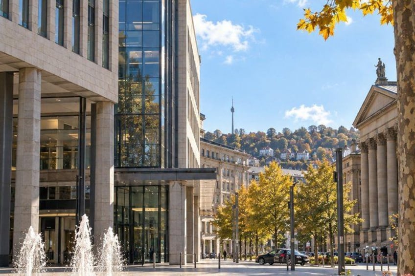A modern building with glass windows, a fountain, and autumn trees. 2