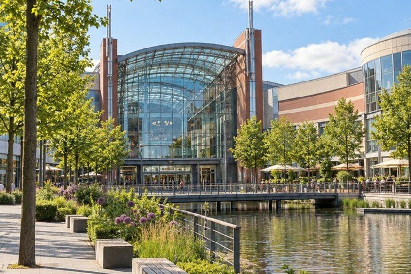 A modern building with a glass facade, surrounded by trees and a water feature. 4