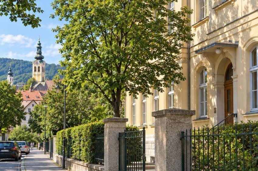 A street with a building, a tree, and a distant church. 5