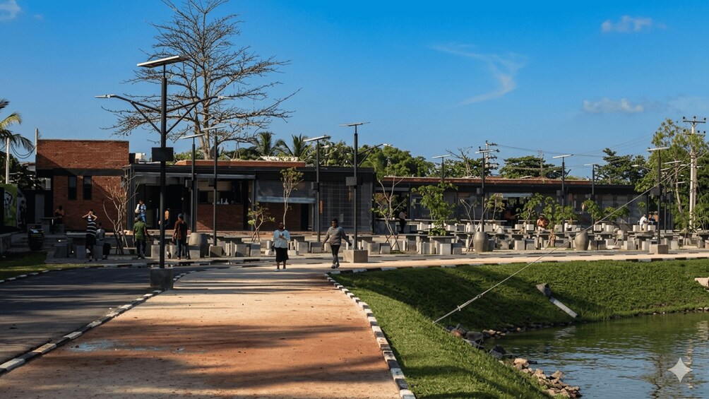 A park with a paved walkway, benches, a small pond, and trees. 2