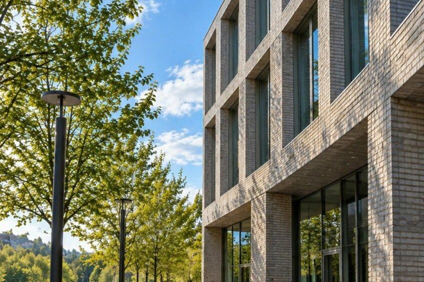A modern building with large windows and a brick facade, surrounded by trees and a clear sky. 5