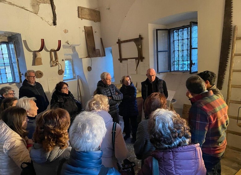 Un grupo de personas en una habitación con decoración rústica, que incluye un serrucho y una ventana con barrotes. 2