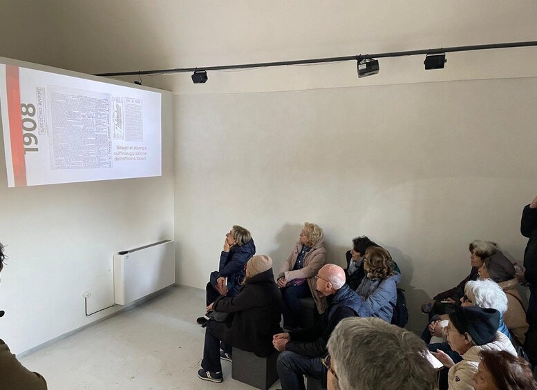 Un grupo de personas sentadas en una sala con una pantalla de proyector mostrando texto. 5