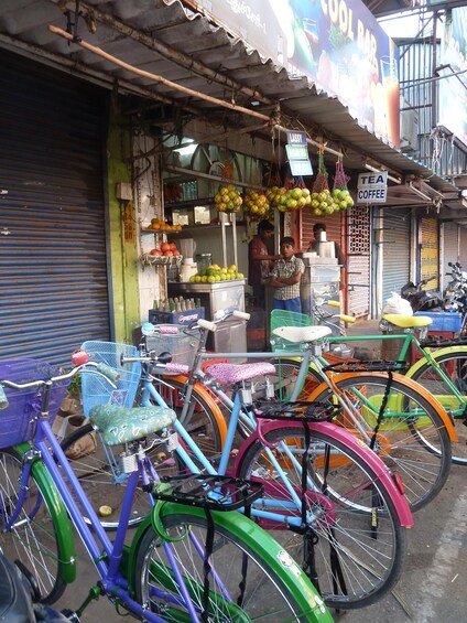 Una calle con bicicletas de colores estacionadas frente a una tienda. 2