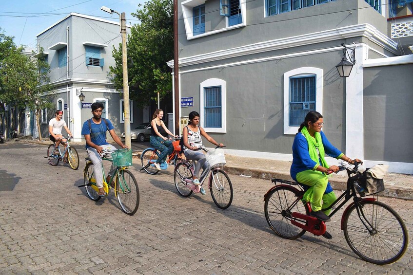 Personas montando bicicletas en una calle adoquinada flanqueada por edificios. 4