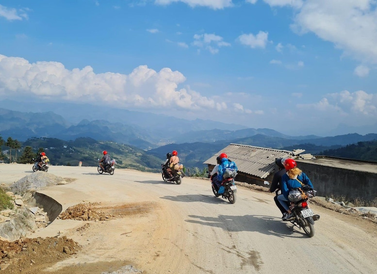 Un groupe de motocyclistes sur un chemin de terre, avec un paysage montagneux en arrière-plan. 1