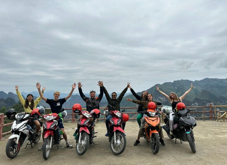 Un groupe de personnes à moto, les bras levés, surplombant un paysage montagneux. 4