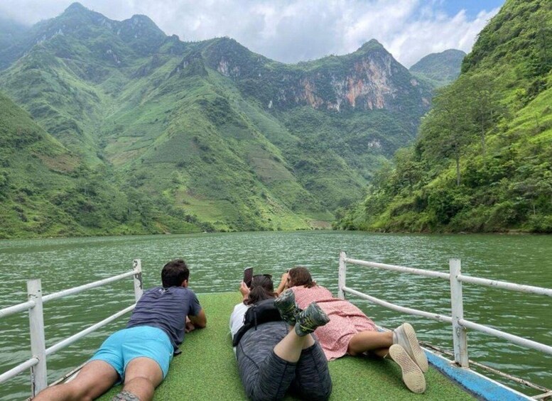 Un groupe de personnes est allongé sur un bateau, avec un paysage montagneux en arrière-plan. 5