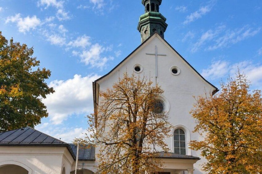 A church with a white facade, a green spire, and a cross. 2