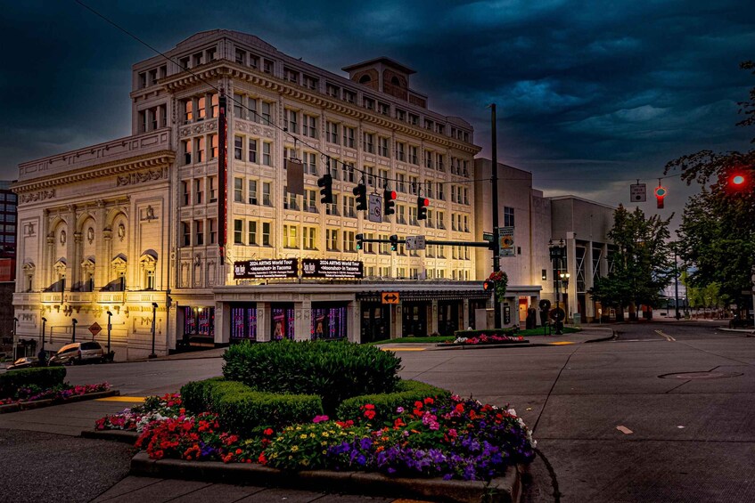 A historic theater with ornate architecture, a street intersection, traffic lights, and a flower bed. 5