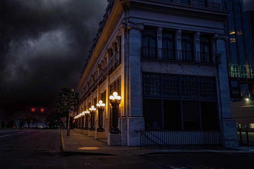 A historic building with ornate columns and large windows, illuminated by street lamps. 4