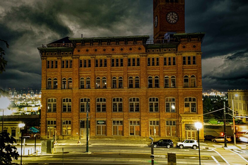 A large brick building with a clock tower, under a dark cloudy sky. 2