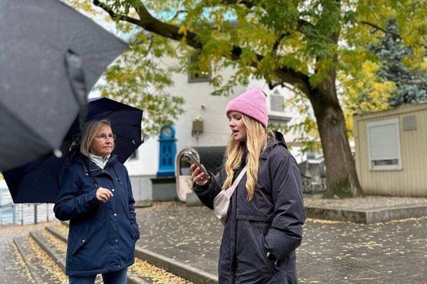 Two people standing on a street, one holding an umbrella. 2